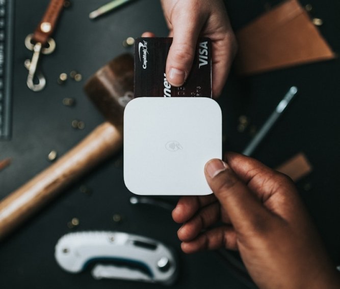 person holding Visa card and white device